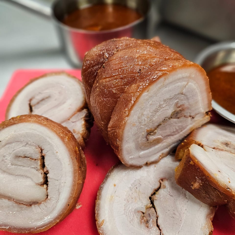 Sliced Vietnamese roasted pork belly with crispy skin on a red cutting board.
