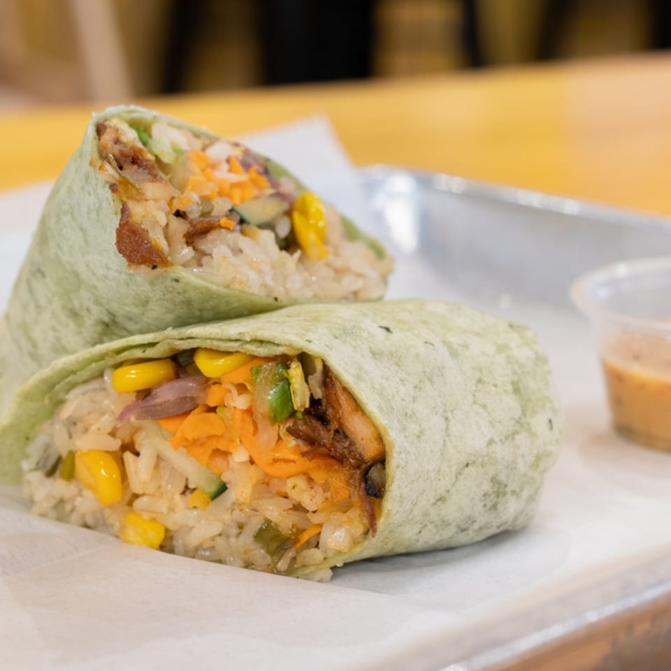 Two SATE Banh Mi & Grille Vietnamese burritos, filled with rice, corn, carrots, and meat, on a tray.