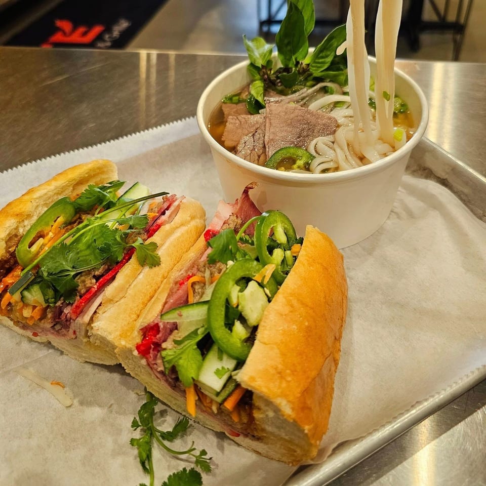 Two SATE Banh Mi sandwiches and a bowl of pho with noodles being lifted.